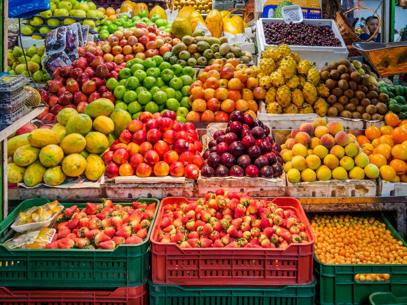 A vibrant market stall displaying piles of fresh tropical fruits and berries