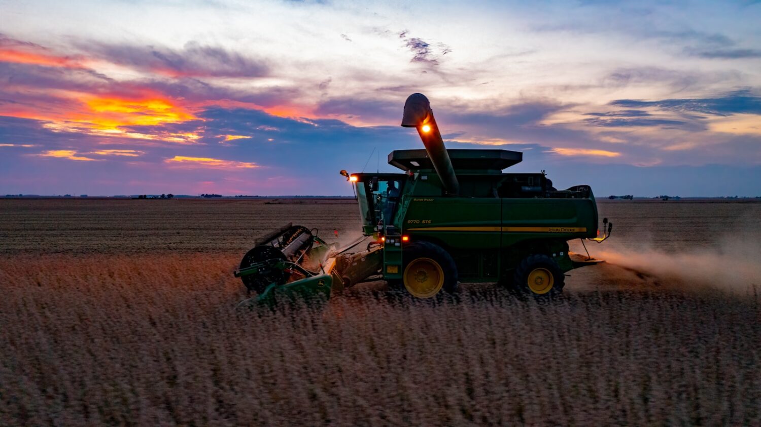 a combine harvesting a field at sunset